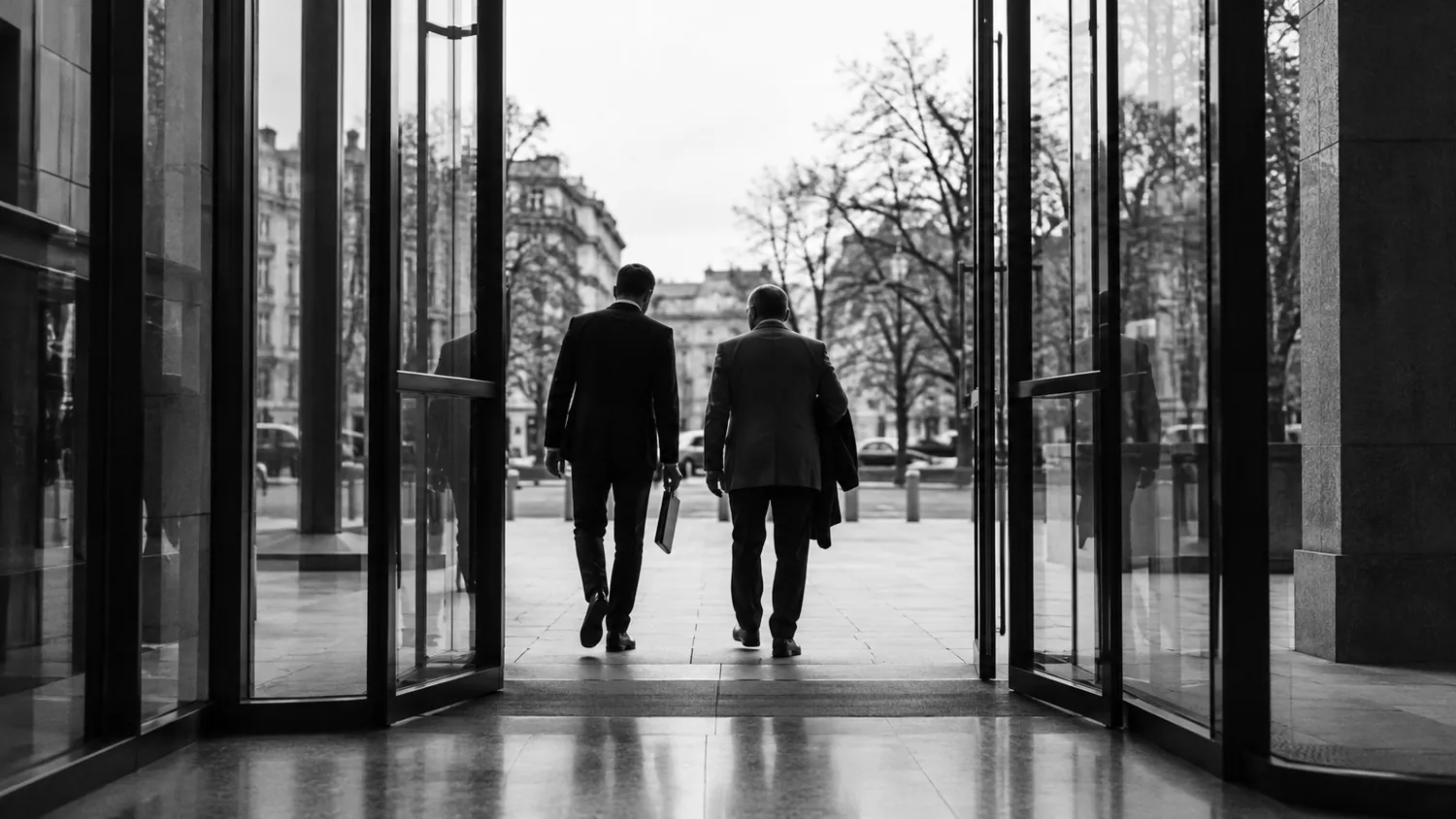 Чоловік з адвокатом виходять із будівлі суду після ухвали про домашній арешт